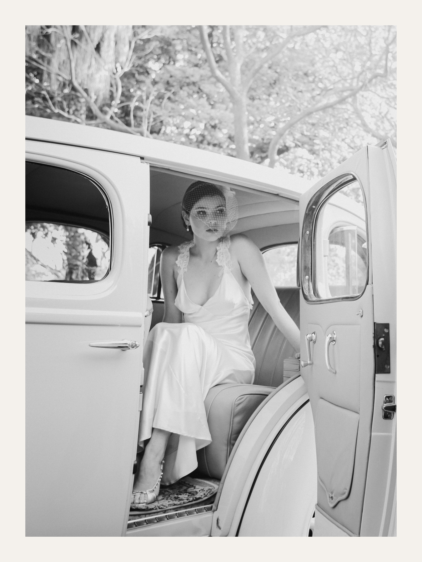 Bride stepping out of a vintage car in dappled shade. Ben Viljoen Photography